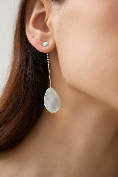 The Dune — close-up of silver-tone oval drop earring worn on an ear