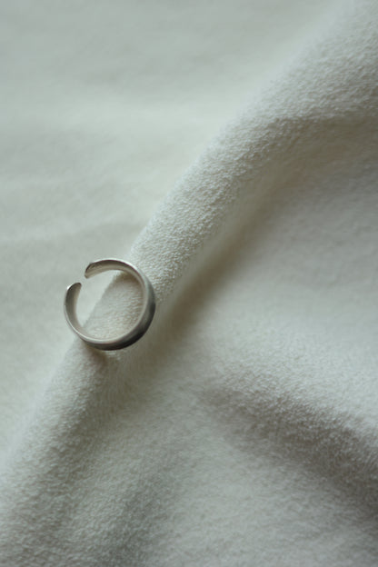 Minimalist Handmade Silver Ring — top view of band on pale fabric
