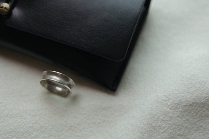 Minimalist Handmade Silver Ring — double-ridge band beside a black case