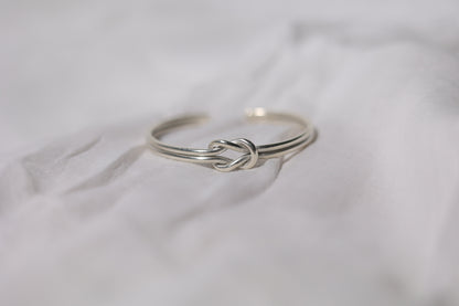 Handcrafted Minimal Style Silver Bangle-The Knot — knot bangle arranged on pale fabric
