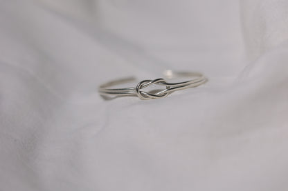 Handcrafted Minimal Style Silver Bangle-The Knot — knot bangle on pale fabric