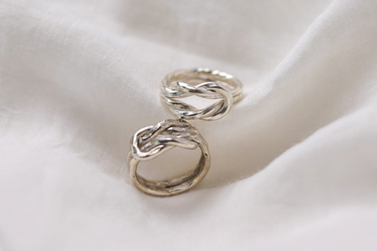 Handcrafted The Knot Ring — two knot rings on pale fabric