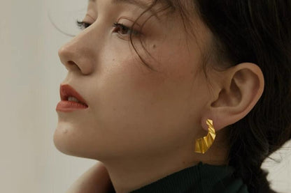 The Origami-Earrings — gold-tone folded earring worn on an ear