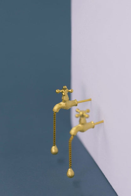 The Tab- Earrings — gold-tone tap-shaped earrings on a display