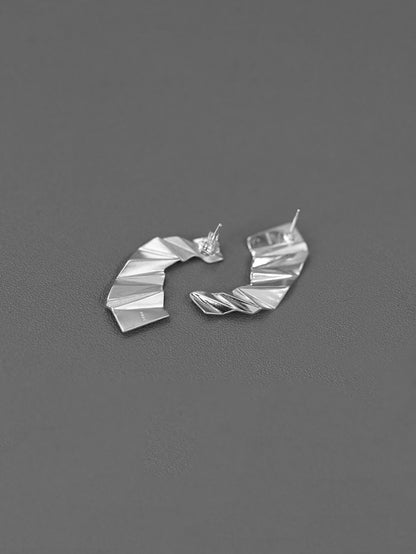 The Origami-Earrings — silver-tone folded earrings on grey surface