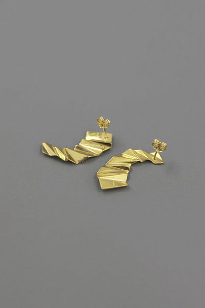 The Origami-Earrings — gold-tone folded earrings on grey surface