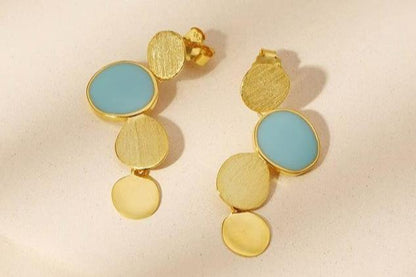 The Stones-Earrings — gold-tone earrings with blue accents on pale surface