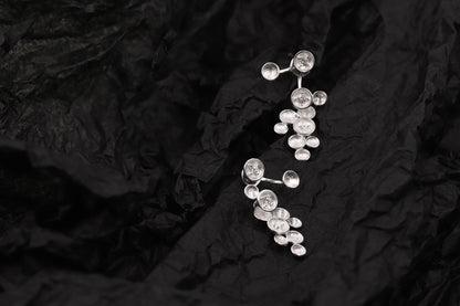 The Stars-Earrings — silver-tone star earrings on textured black surface