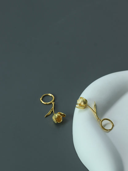 The Tulips-Earrings — gold-tone tulip earrings beside a plate