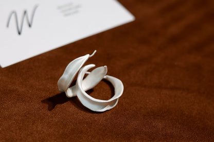 The Leaves-Earrings — leaf-shaped hoop earrings on brown surface