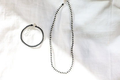 Handwoven Silver Set — necklace and bracelet arranged on pale fabric