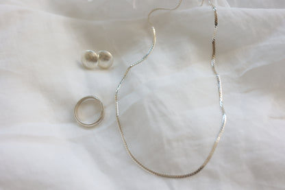 The Minimalist Set — smooth necklace, round studs and ring arranged on fabric