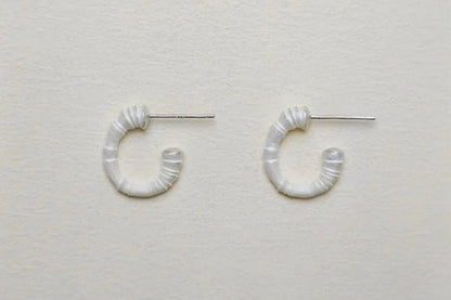 The Seashell-Ear Hoop — pair of open textured hoops on pale fabric