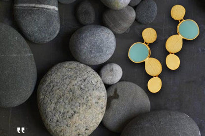 The Stones-Earrings — gold-tone earrings with blue accents beside dark pebbles