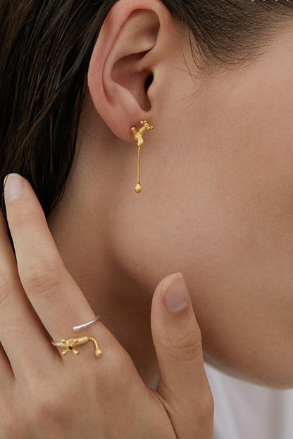 The Tab- Earrings — close-up of gold-tone tap-shaped earring worn on an ear