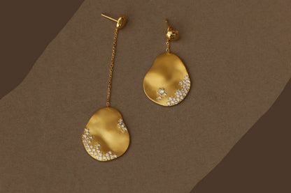 The Dune — close-up of gold-tone oval drop earrings