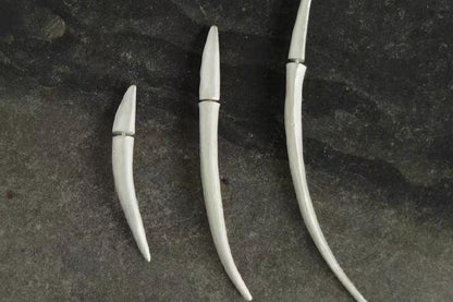 The Bamboo Leaf-Ear Stud — three curved leaf-shaped studs on dark surface