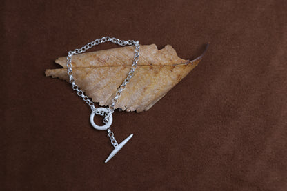 Handcrafted The Minimalist Basic Bracelet — chain bracelet with toggle clasp on dried leaf
