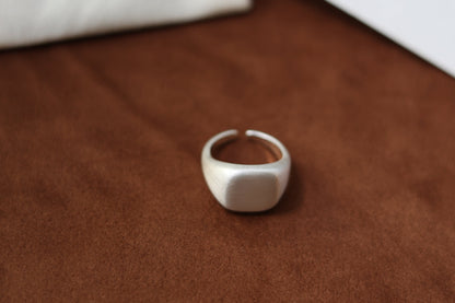 The Minimal Signet Ring — silver-tone signet ring on brown surface