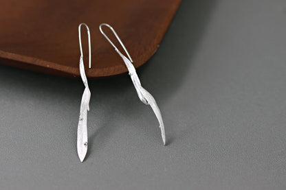 Wind Earrings — silver-tone elongated earrings beside a bowl