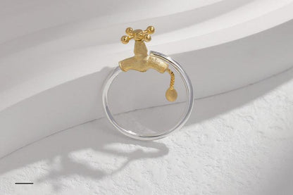 The Tab-Ring — silver-tone band with gold-tone tap detail beside a white step