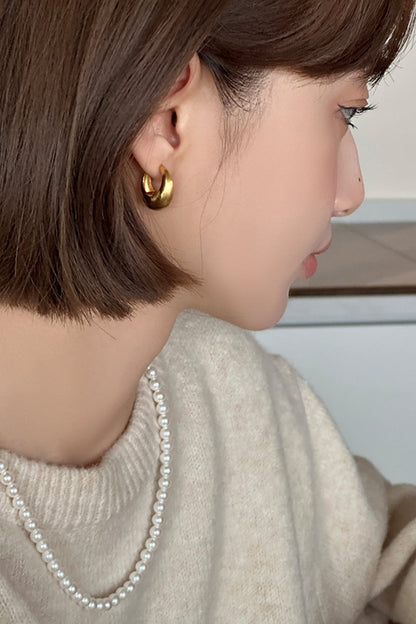 The Minimalist Basic Hoop - The Drop — gold-tone rounded hoop earring worn on an ear