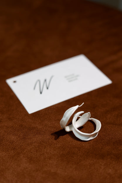 The Leaves-Earrings — leaf hoops beside branded card