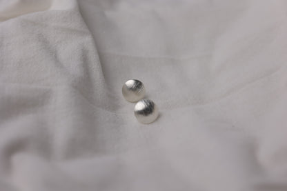 Minimalist Handcrafted Frosted Silver Ear Stud — round frosted studs on pale fabric