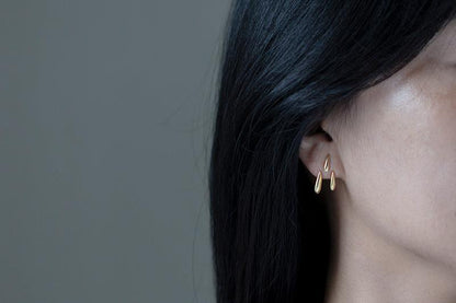 Rain Drops Earrings — gold-tone drop earring worn on an ear