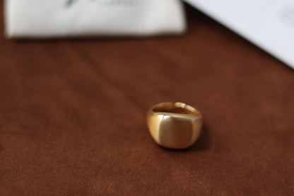 The Minimal Signet Ring — gold-tone signet ring on brown surface