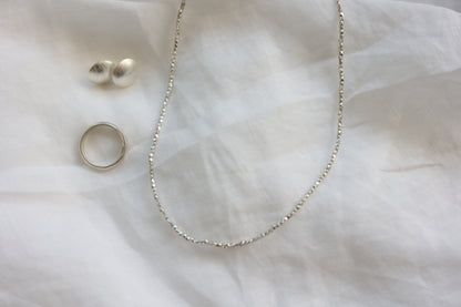 The Minimalist Set — beaded necklace, round studs and ring arranged on fabric