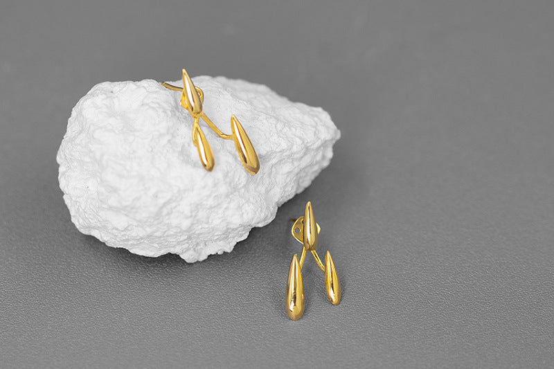 Rain Drops Earrings — gold-tone earrings arranged beside a white stone