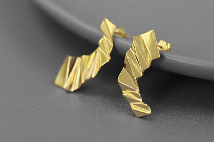 The Origami-Earrings — gold-tone folded earrings beside a plate