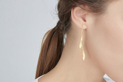 Wind Earrings — gold-tone elongated earring worn on an ear