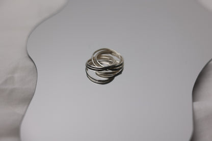 Handcrafted Interlocked Round Silver Ring — interlocked bands on reflective surface