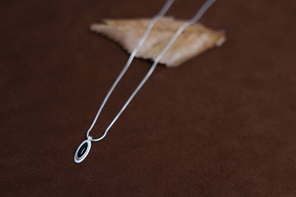 The B & W Onyx Necklace — black oval pendant necklace on brown surface