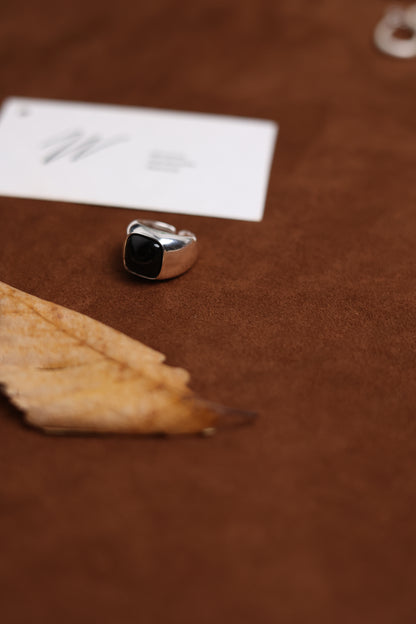The Smoky Quartz Signet Ring — signet ring beside leaf and card on brown surface