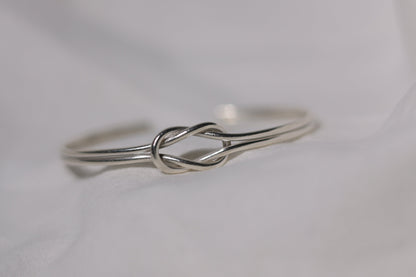 Handcrafted Minimal Style Silver Bangle-The Knot — close-up of knot design on pale fabric