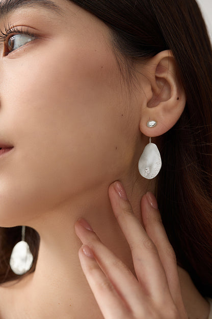 The Dune — silver-tone oval drop earring worn on an ear