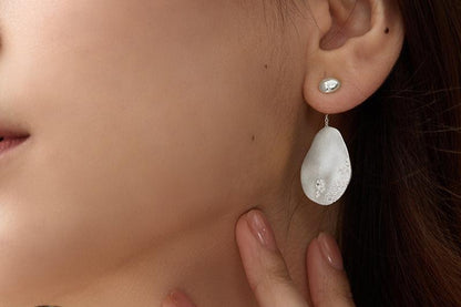 The Dune — silver-tone oval drop earring worn on an ear