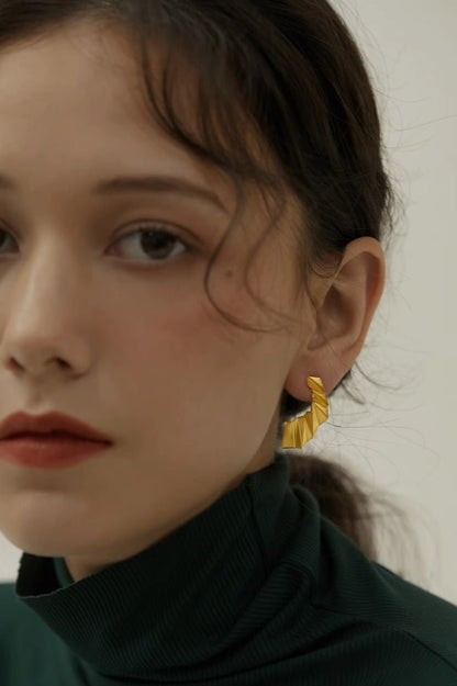 The Origami-Earrings — close-up of gold-tone folded earring worn on an ear