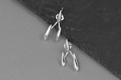 Rain Drops Earrings — silver-tone drop earrings beside a dark stone