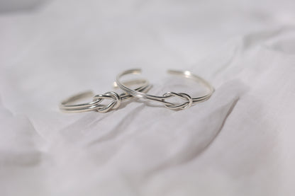 Handcrafted Minimal Style Silver Bangle-The Knot — two knot bangles on pale fabric