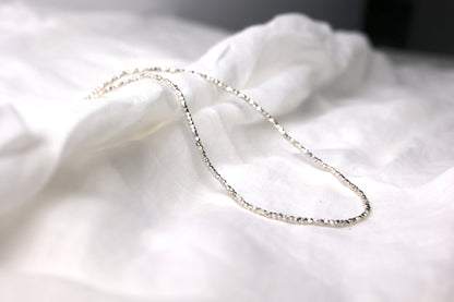 Minimalist Handcrafted Silver Beaded Necklace- Thin — fine beaded necklace arranged on pale fabric