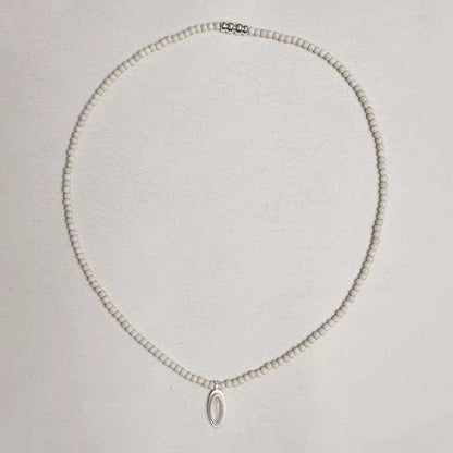 The White- Stone Necklace — full necklace arranged in a loop on a pale surface