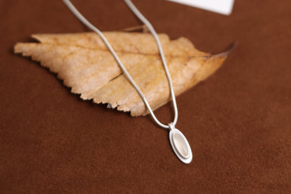 The B & W Onyx Necklace — white oval pendant necklace on dried leaf