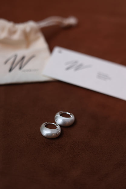 The Minimalist Basic Hoop - The Drop — silver-tone rounded hoops beside a pouch and brand cards
