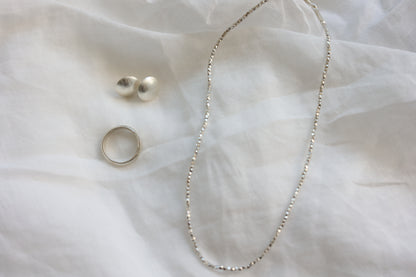The Minimalist Set — beaded necklace, studs and ring displayed on fabric