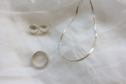 The Minimalist Set — smooth necklace, studs and ring displayed on fabric