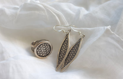 The Weaved Set — woven-pattern round ring and leaf-shaped earrings on fabric